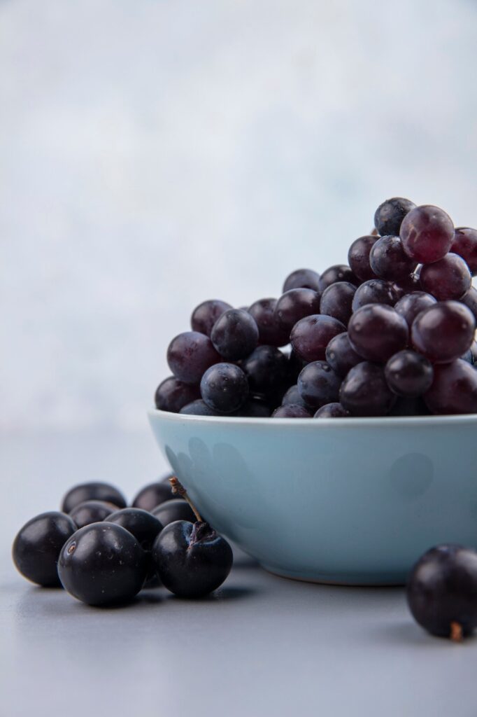 side view fresh black grapes blue bowl grey background 141793 49514